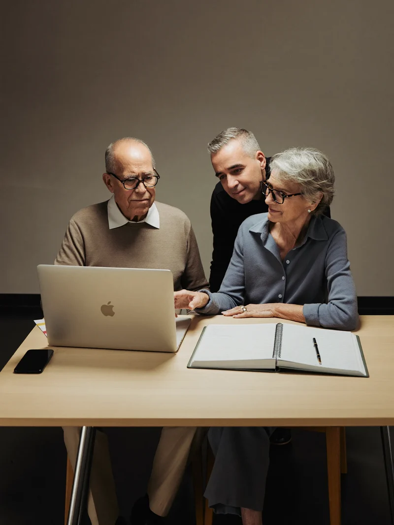 Coppia di anziani al laptop con un volontario accanto